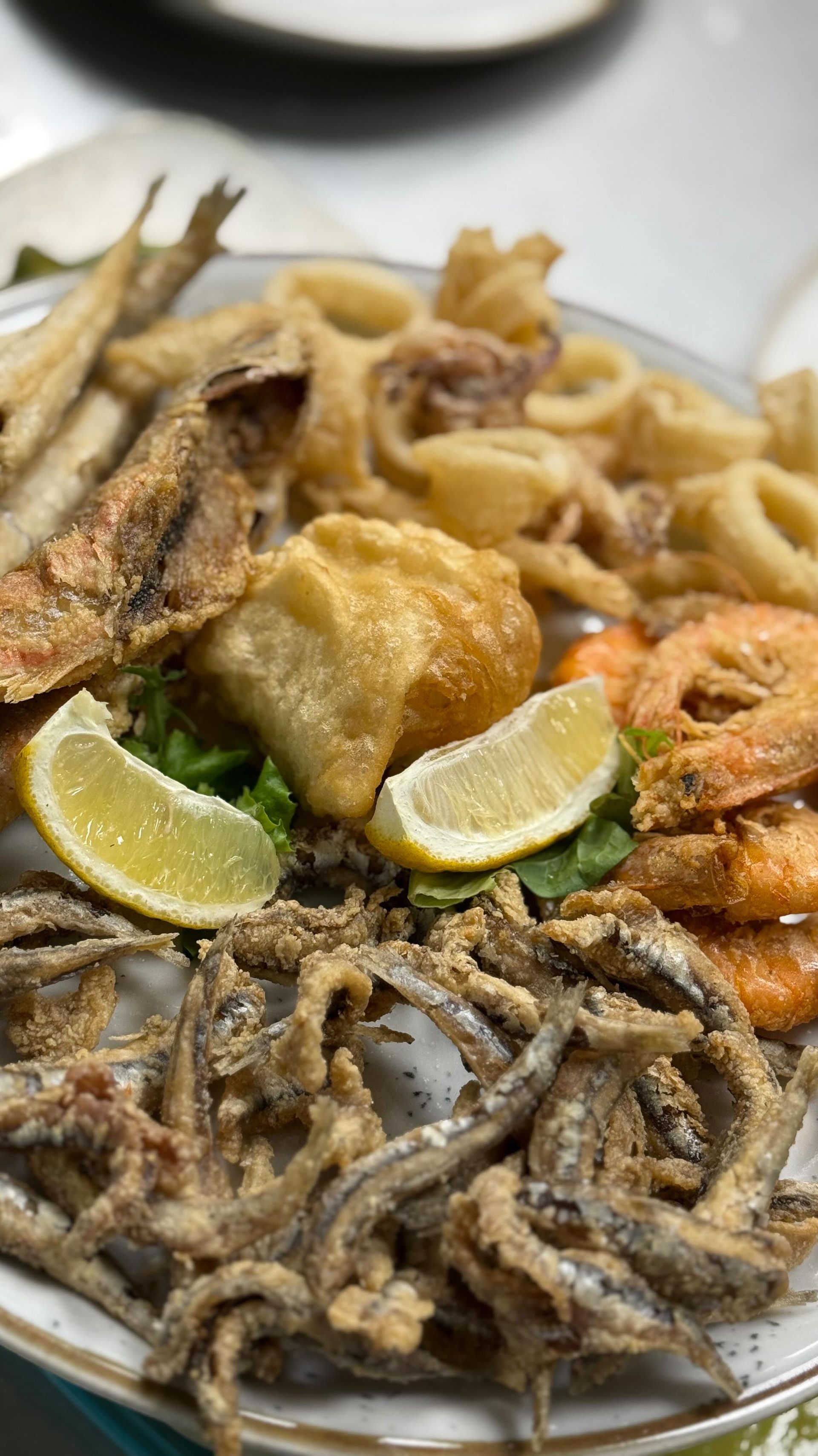 Piatto di frutti di mare fritti con calamari, gamberi e pesce, guarnito con limone.