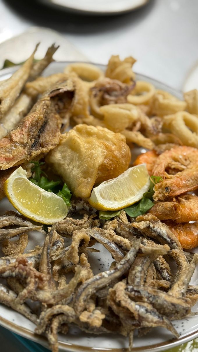 Piatto di frutti di mare fritti con calamari, gamberi e pesce, guarnito con limone.