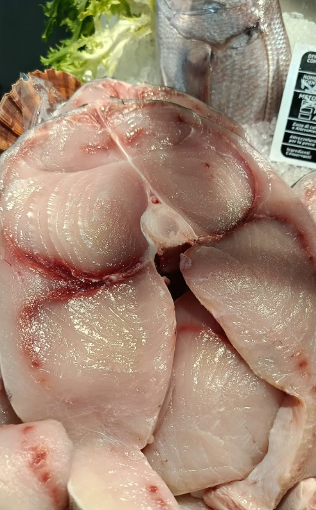 Filetti di pesce crudo, rosa pallido con vasi sanguigni visibili, primo piano.