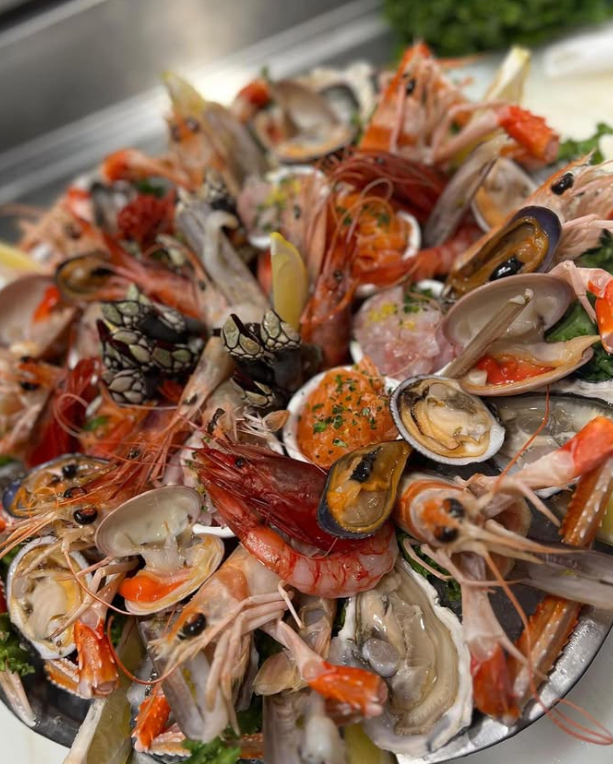 Piatto di frutti di mare: gamberi, vongole, cozze, ostriche, con guarnizione di limone su un vassoio d'argento.