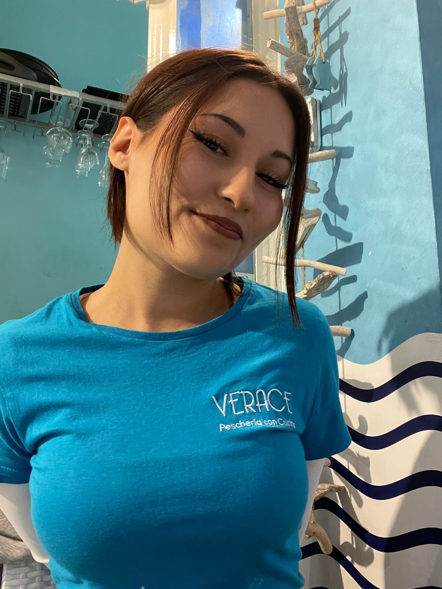 Donna sorridente, indossa una maglietta blu con la scritta