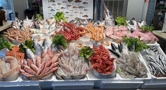 Frutti di mare freschi sul ghiaccio, tra cui pesci, piccoli polpi e gamberi rossi.