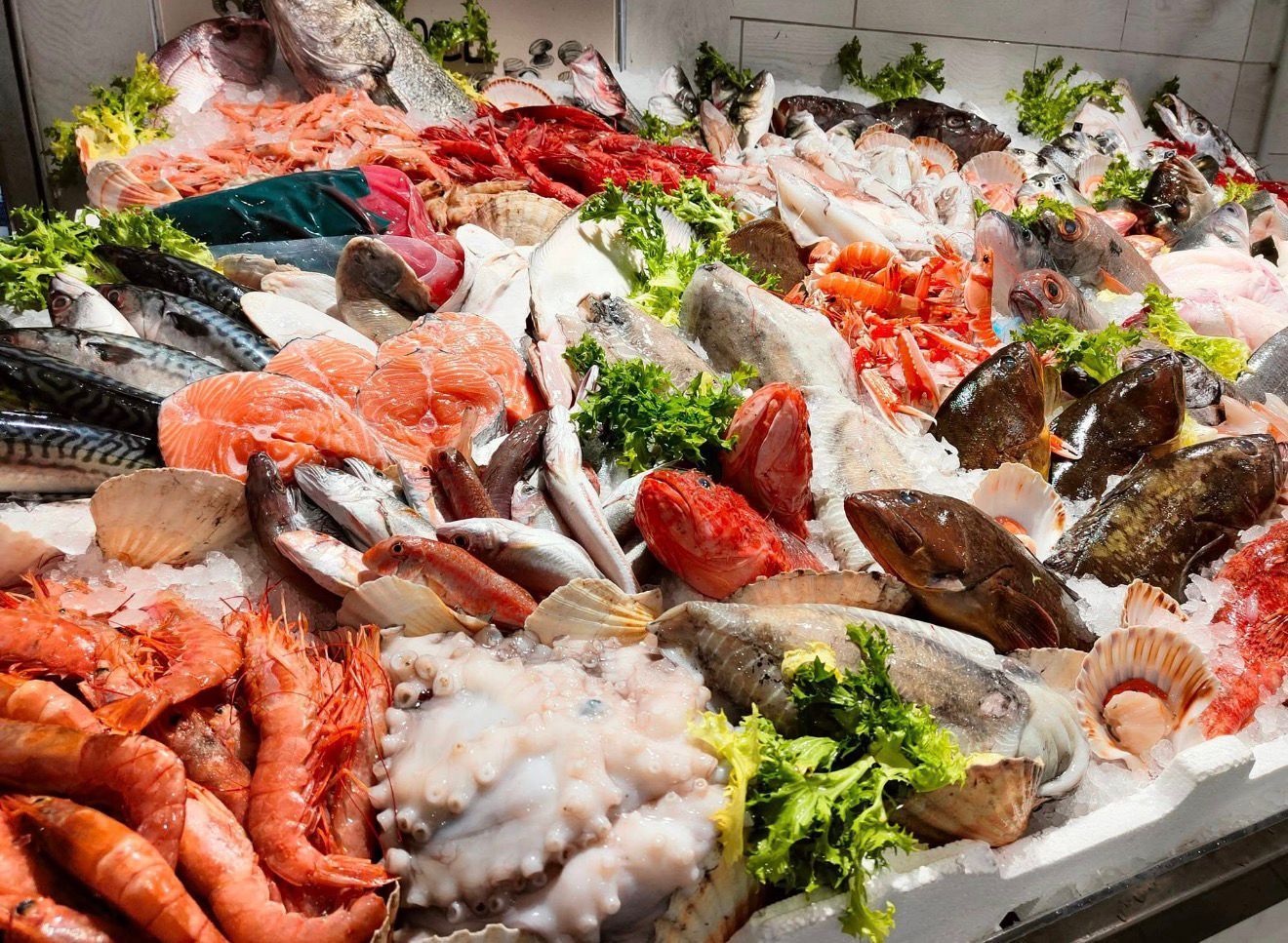 Pesce fresco sul ghiaccio, primo piano con occhi e squame rossi, in un ambiente di mercato.