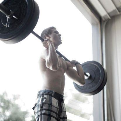 Male athlete performing an Olympic lift at Kansas Strength and Performance gym, showcasing powerful lifting technique in a focused setting.
