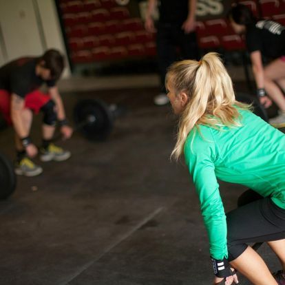 Female fitness coach instructing a male athlete on proper deadlift techniques in a gym, fostering skill development and safe training practices.