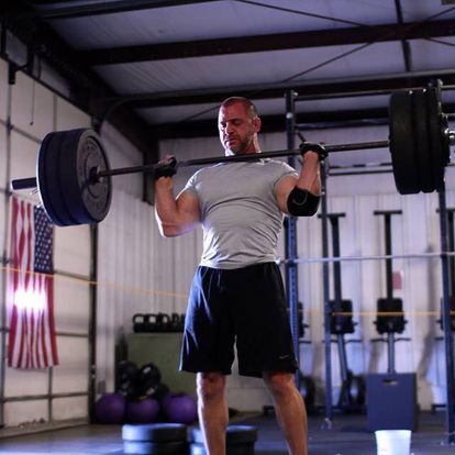 Strong male athlete performing a heavy barbell lift in a gym, focusing on strength training.