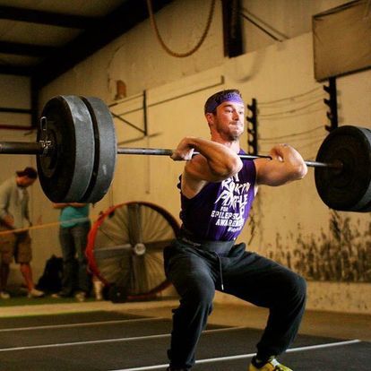 Male athlete performing an Olympic lift at Kansas Strength and Performance gym, showcasing powerful lifting technique in a focused setting.