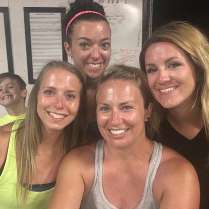 A group of women are posing for a picture in front of a whiteboard.