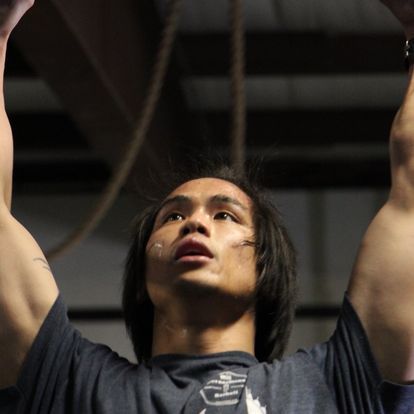 Focused young male athlete looking up while preparing for a pull-up at a fitness facility, showcasing determination and strength.