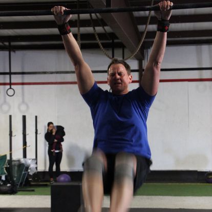 Man in blue completing a dynamic jumping exercise at an indoor gym, demonstrating power and agility.
