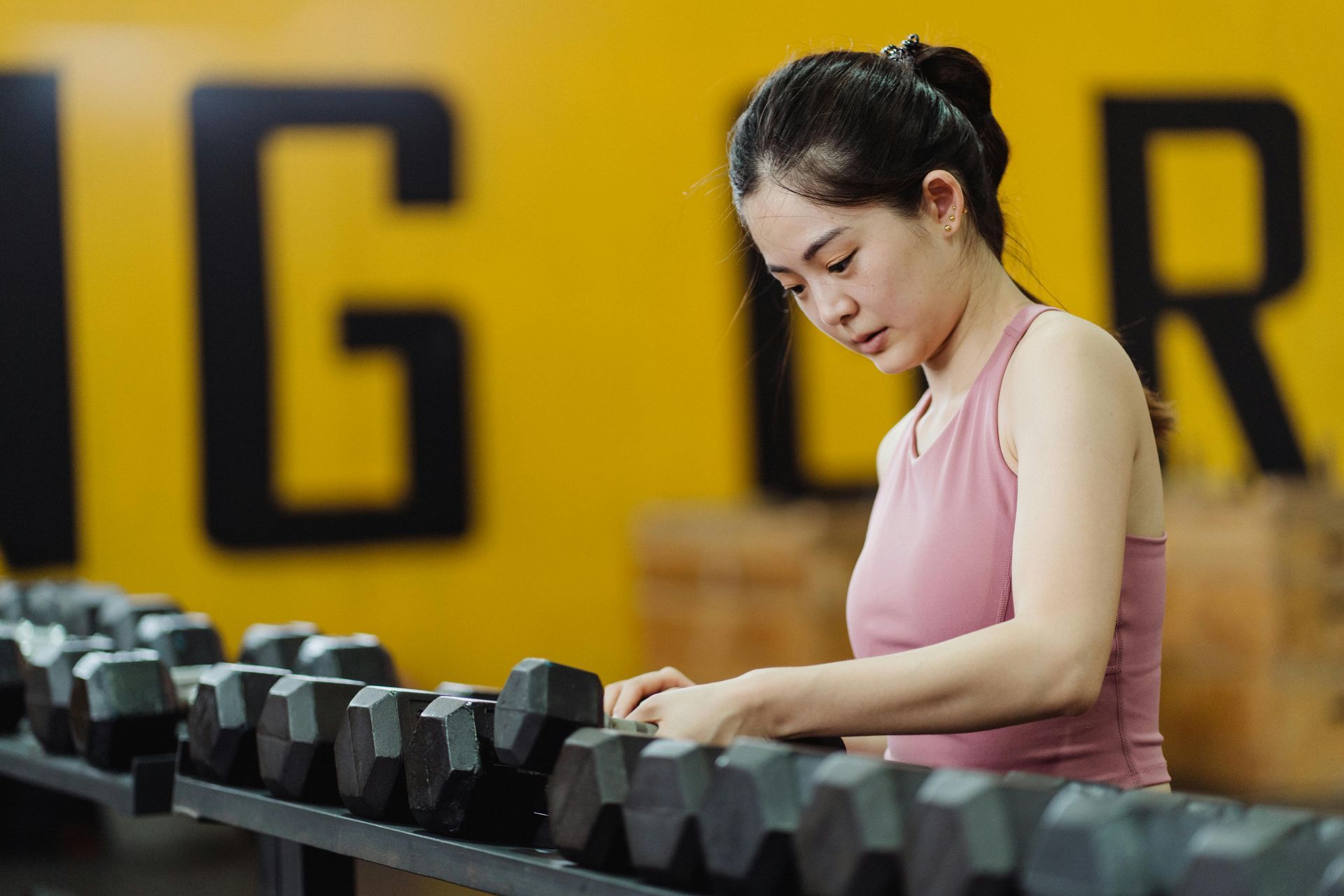 Female gym member choosing dumbbells at beginner-friendly fitness center