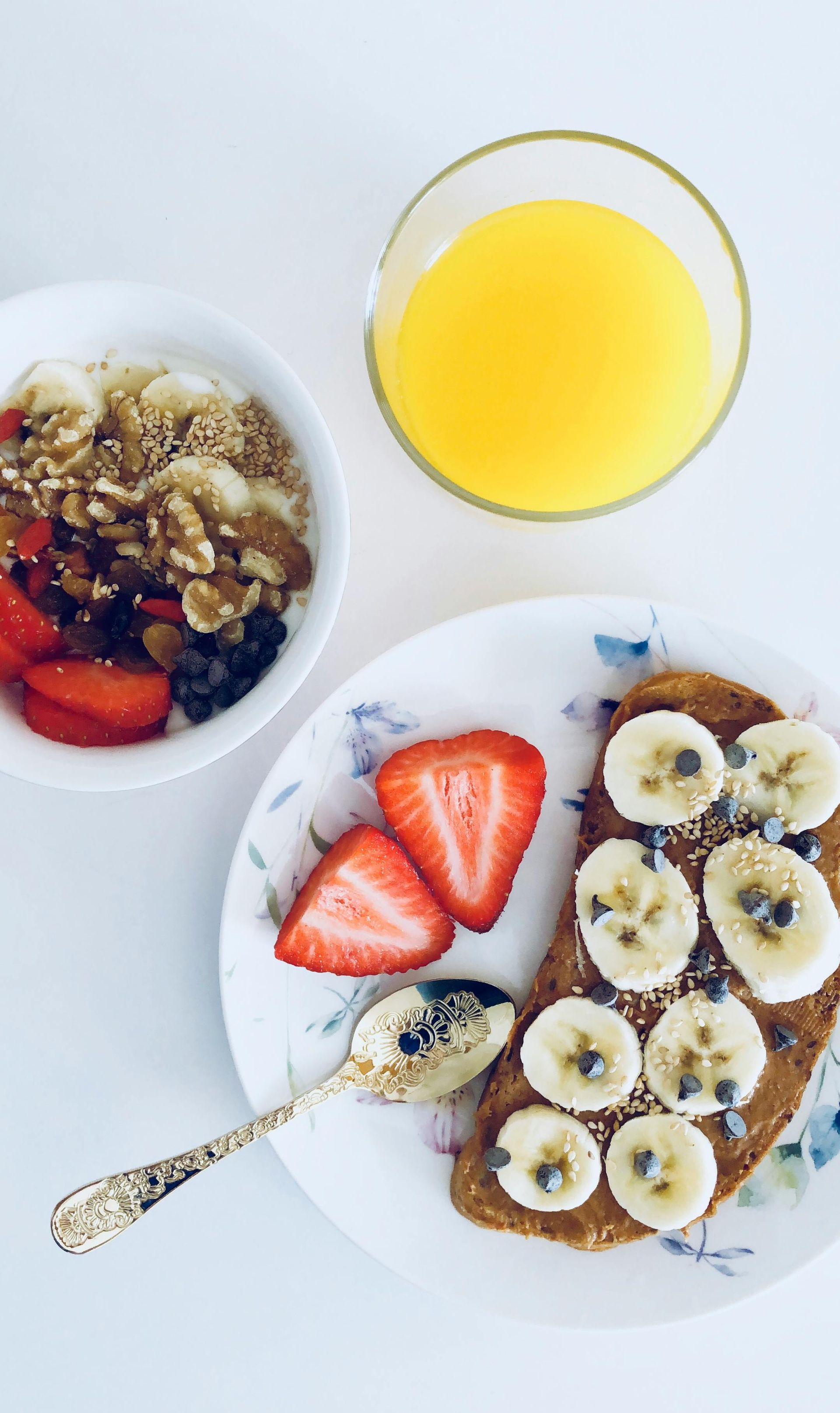 A nutritious breakfast plate with oatmeal, fruits, and toast topped with bananas and seeds, paired with a glass of orange juice, perfect for a post-workout meal.