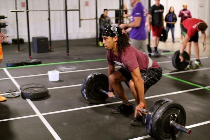 Male athlete performing an Olympic lift at Kansas Strength and Performance gym, showcasing powerful lifting technique in a focused setting.