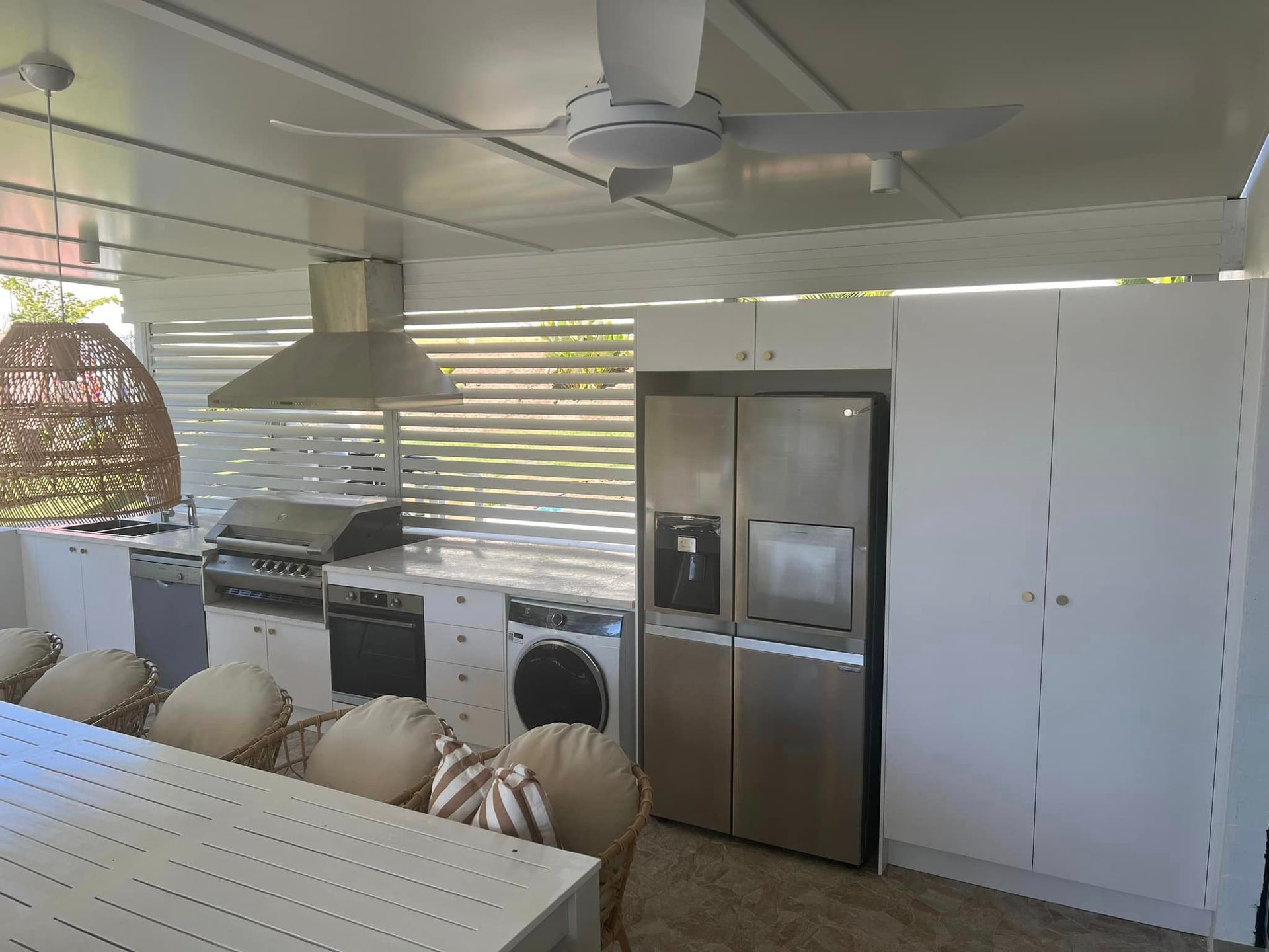 A kitchen with a refrigerator , washer and dryer , and a ceiling fan.