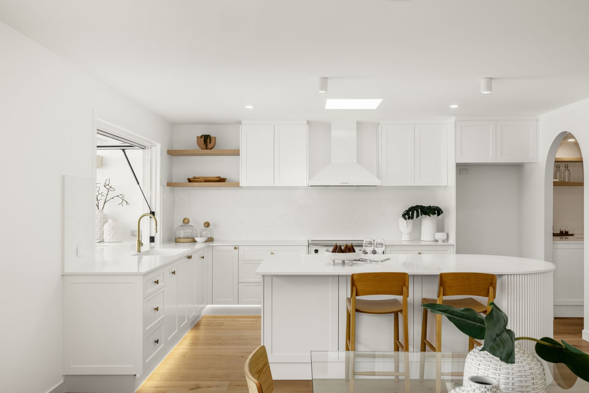 A kitchen with white cabinets , a stove , a table and chairs.