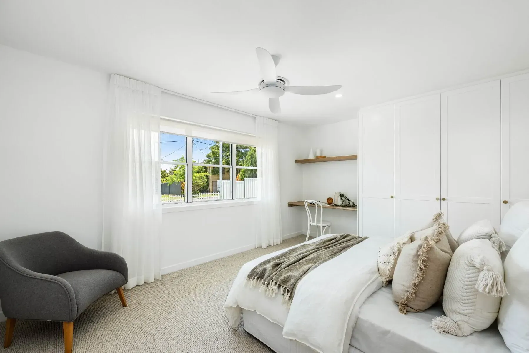 A bedroom with a bed , chair and ceiling fan.