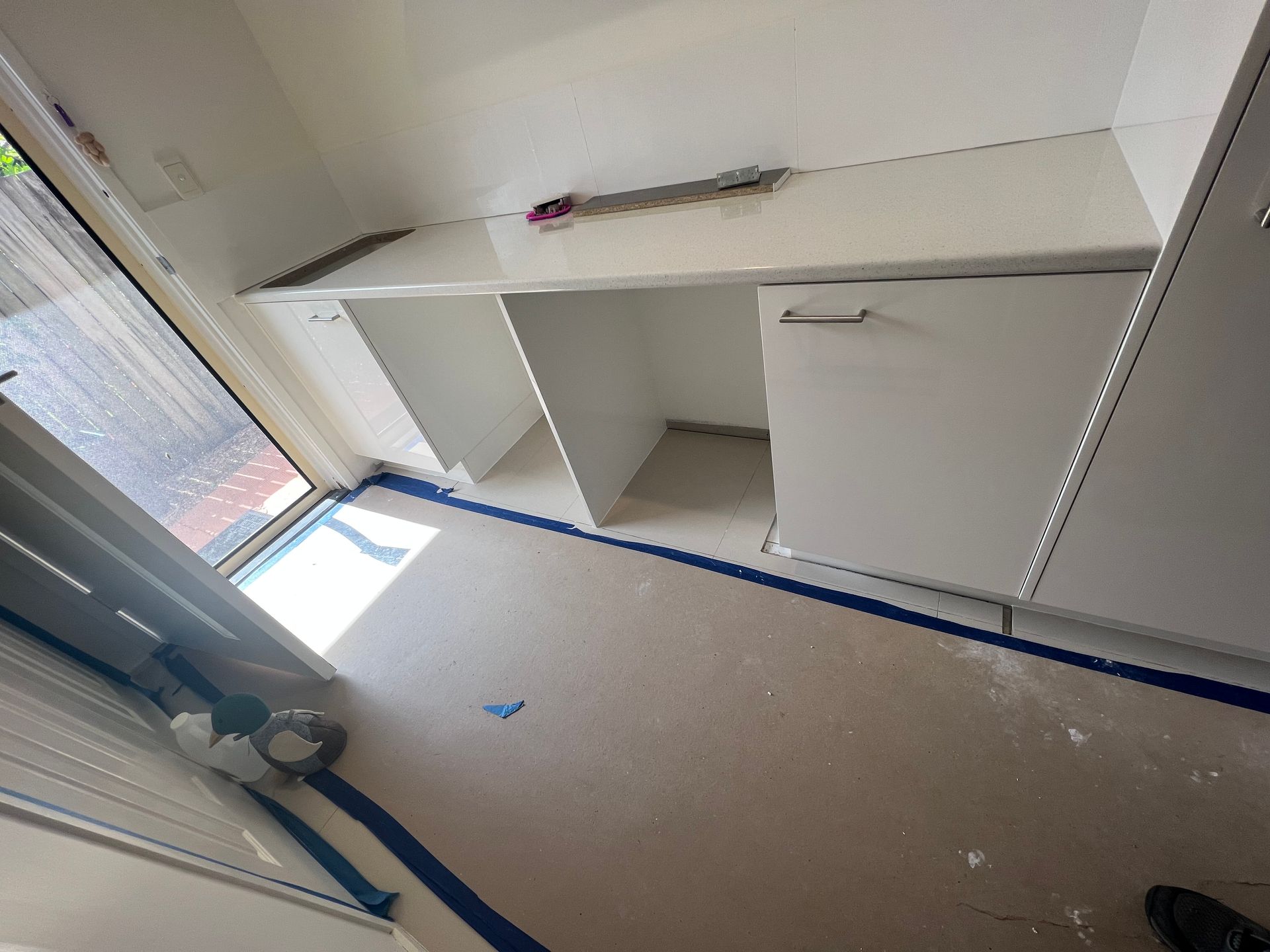 A room with white cabinets and blue tape on the floor