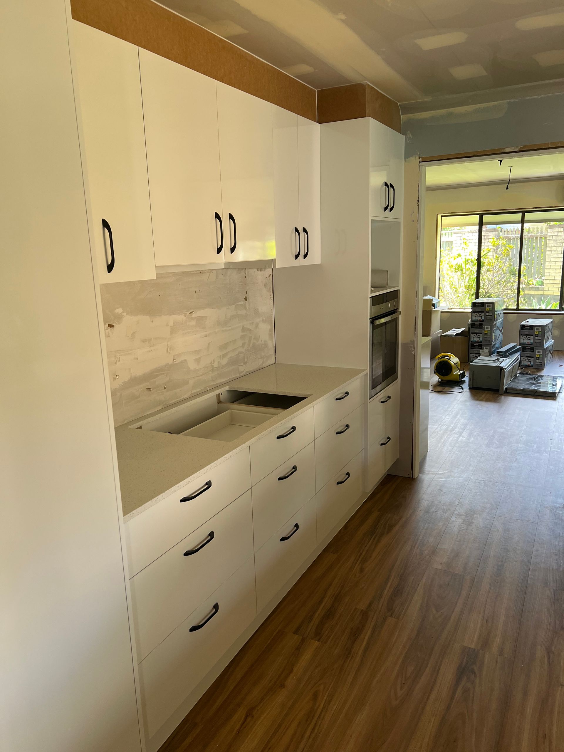 A kitchen with white cabinets and wooden floors is being remodeled.