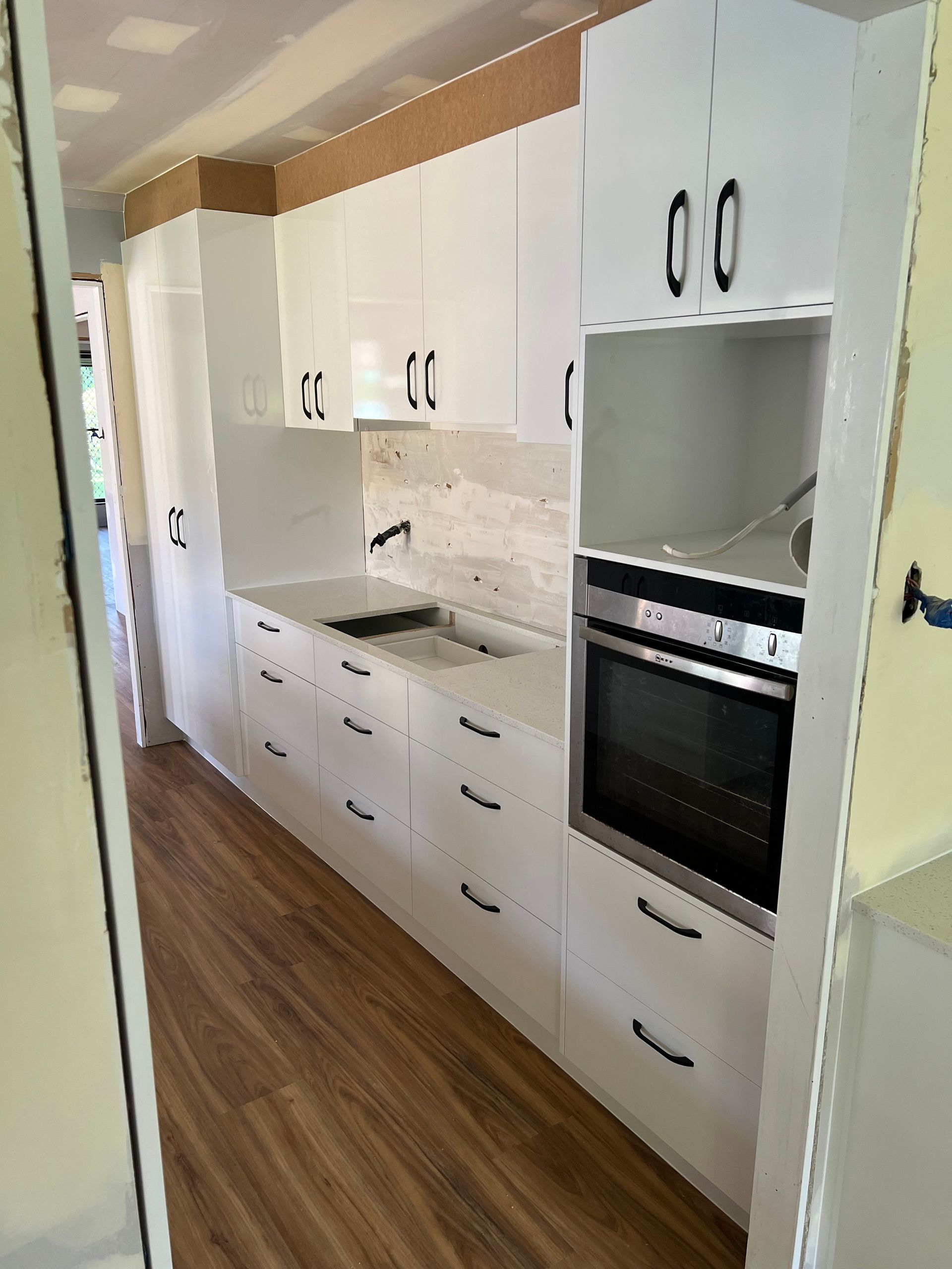 A kitchen with white cabinets , a sink , and an oven.