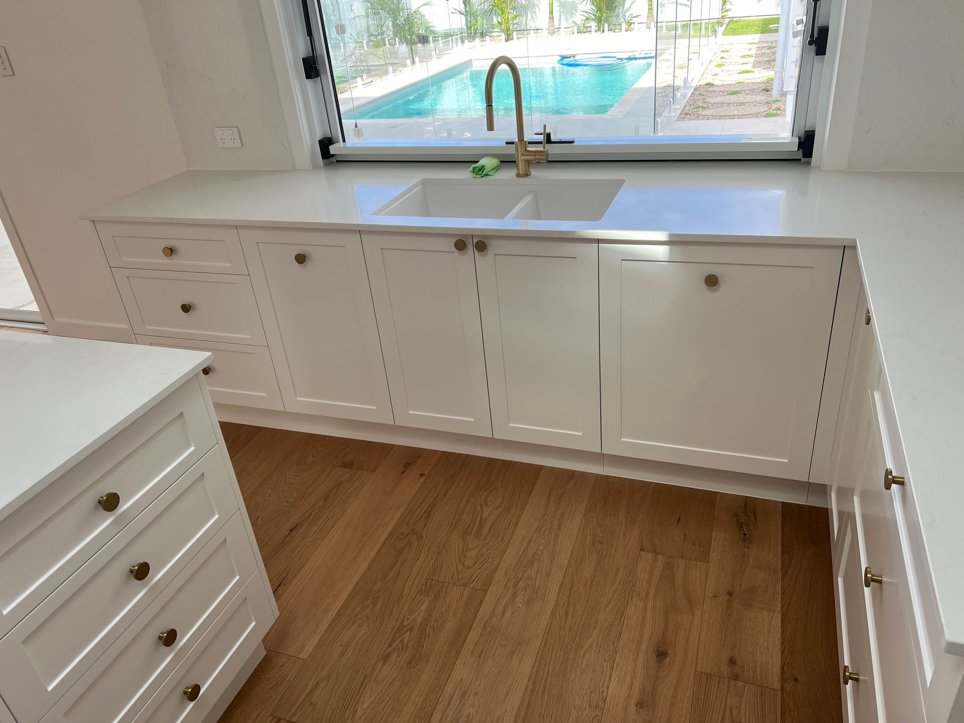 A kitchen with a sink and a window overlooking a pool.