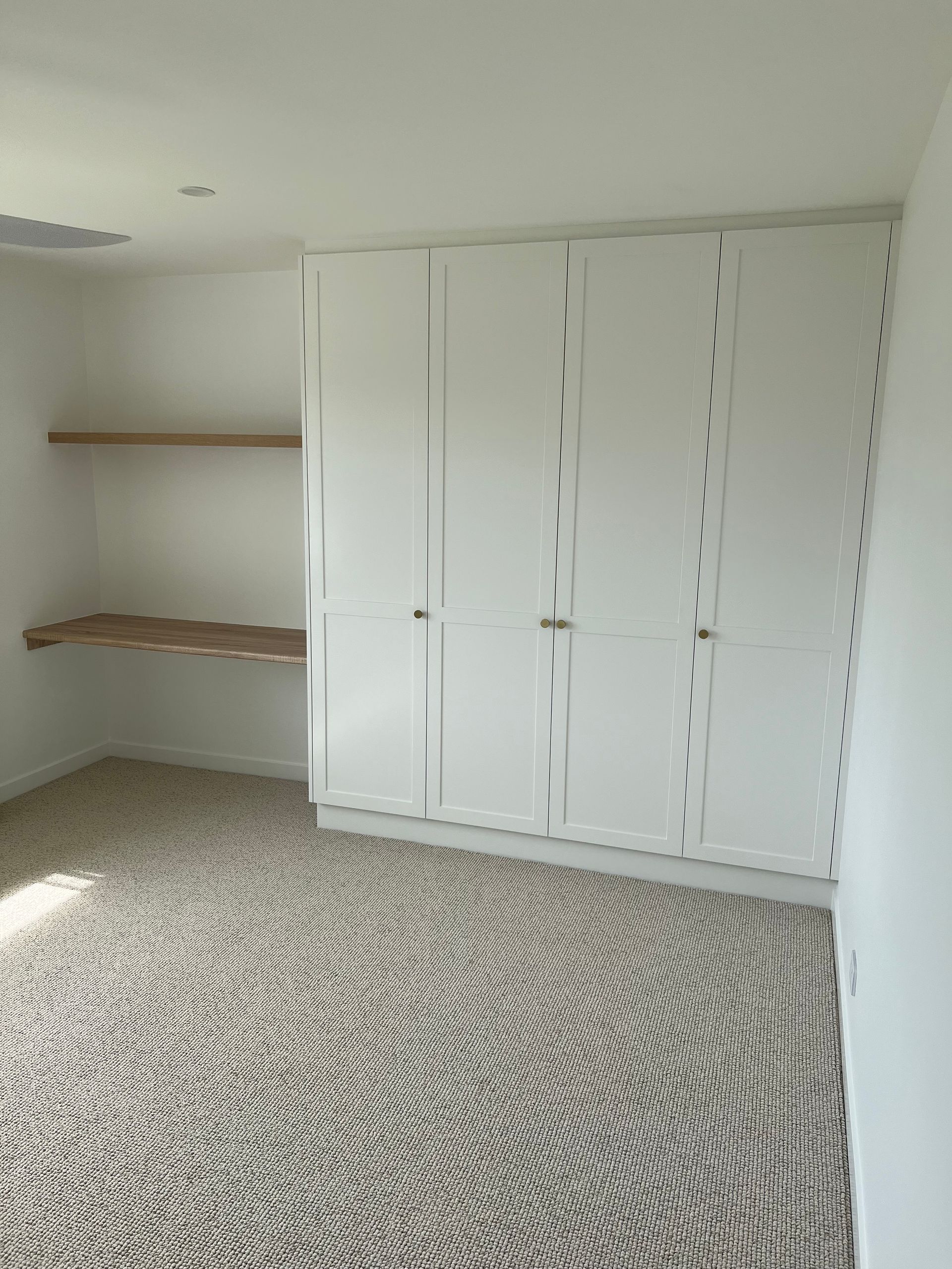 An empty room with white cabinets and a carpeted floor.