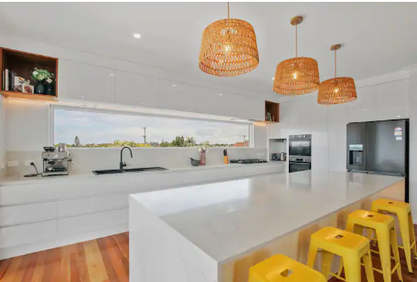 A kitchen with white cabinets and yellow stools