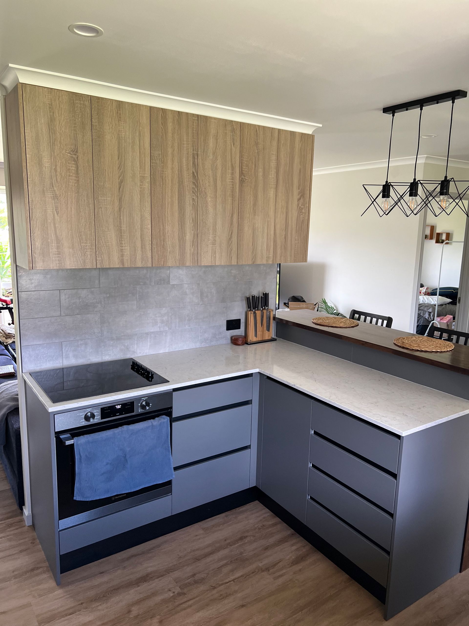 A kitchen with gray cabinets , a stove , and a counter top.