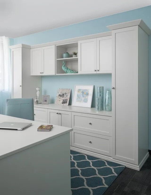 A white desk with a laptop on it in a room with blue walls.