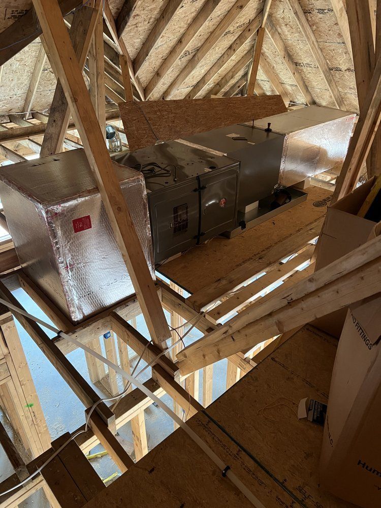An HVAC air handler and ductwork installed on a wooden platform within an unfinished attic space.