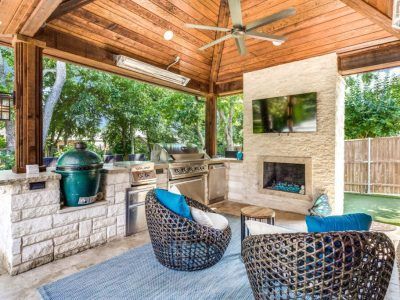 There is a fireplace in the backyard with a ceiling fan.