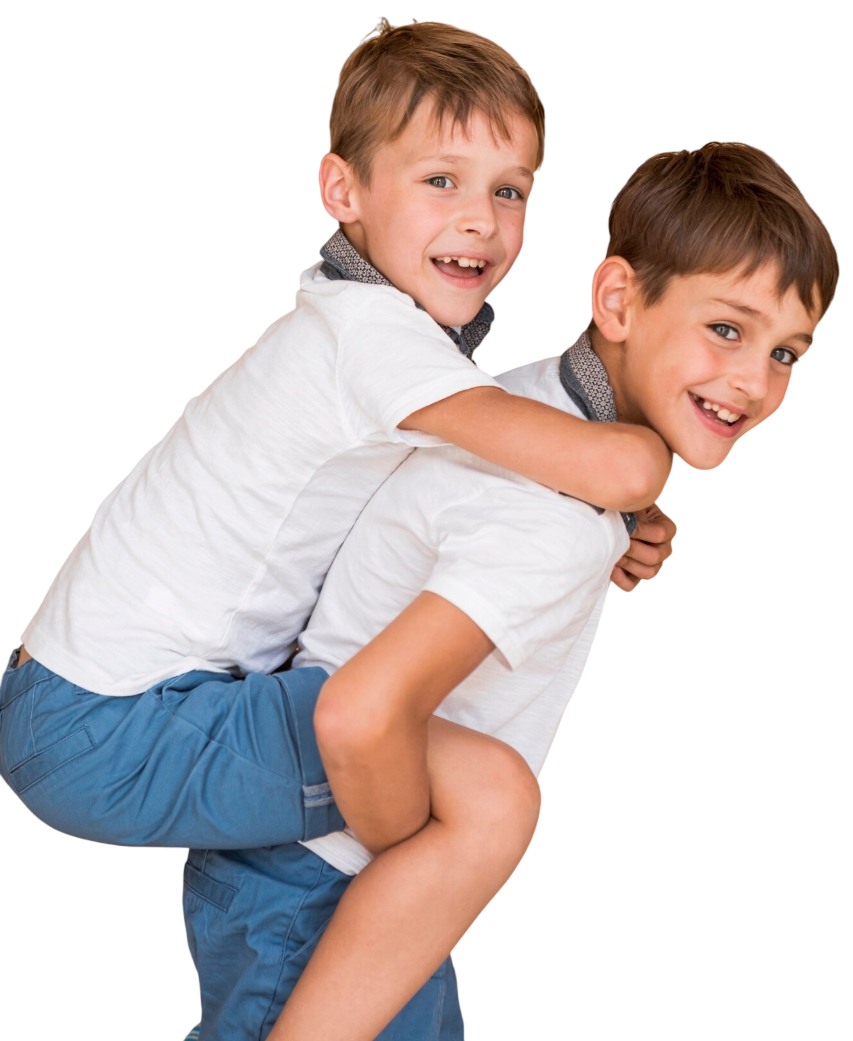 Two boys, one giving the other a piggyback ride, both smiling.