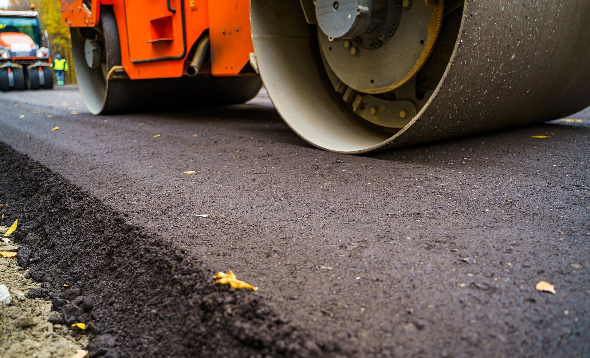 Road roller compacting fresh asphalt on a road.