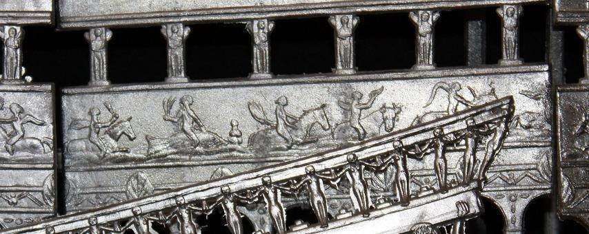 A metallic frieze featuring relief carvings of figures riding horses, separated by vertical pillars and decorative motifs.