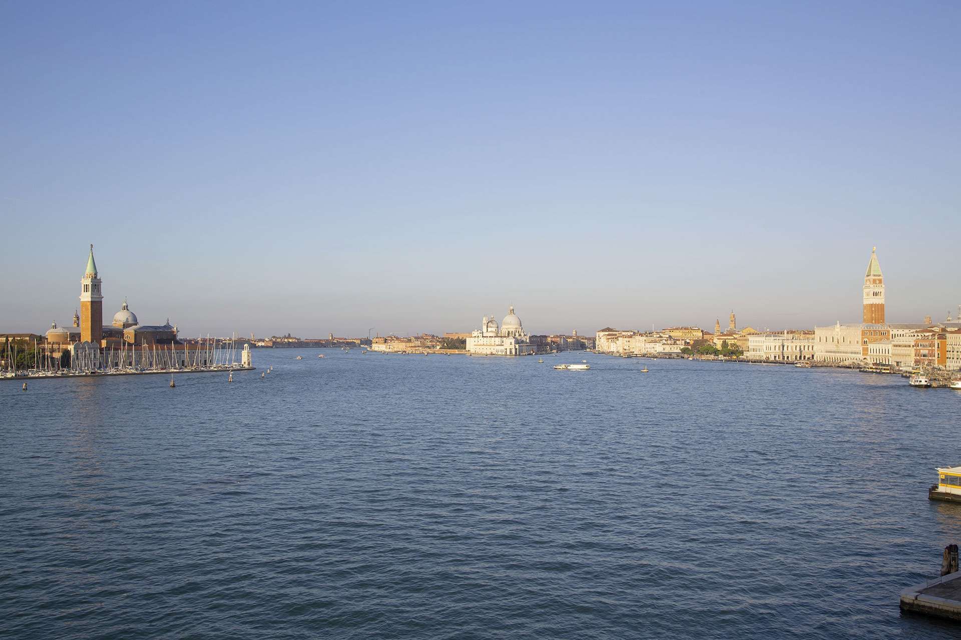 A wide-angle view across a Venetian lagoon, featuring the San Giorgio Maggiore church and the Venice skyline.