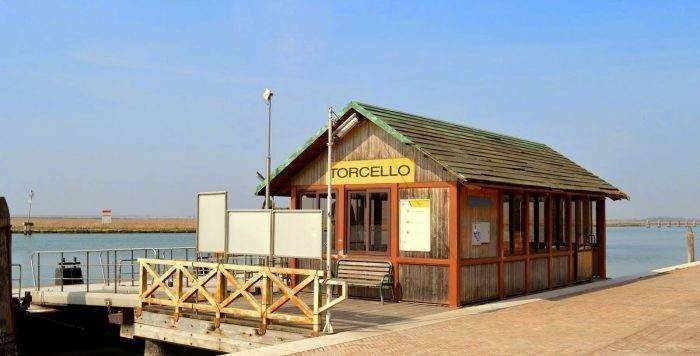 A wooden water bus stop with a green roof labeled 
