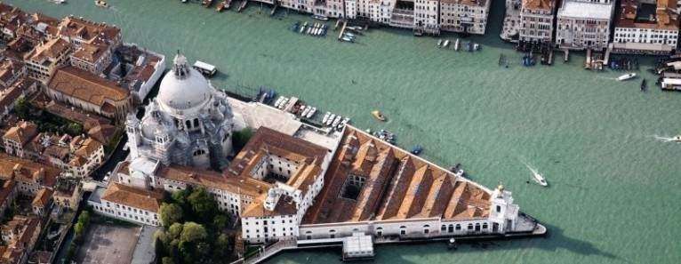 Aerial view of the domed Santa Maria della Salute church at the tip of a triangular peninsula in Venice, Italy.