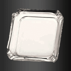 Un cenicero de cristal cuadrado transparente sobre un fondo negro.