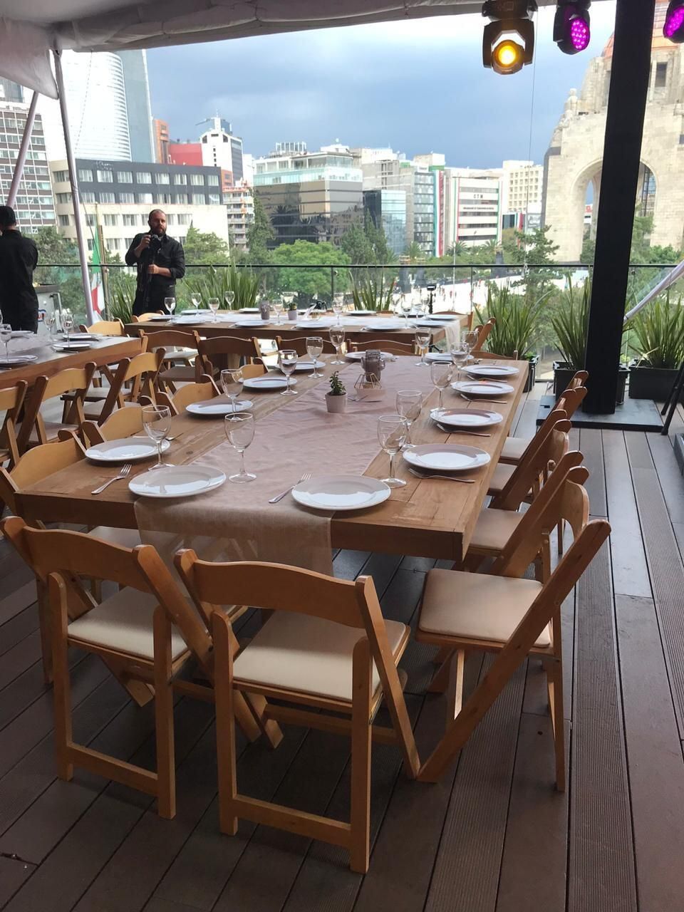 Una larga mesa de madera con platos y vasos encima.