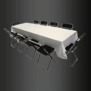 Una mesa larga con un mantel blanco y sillas negras.