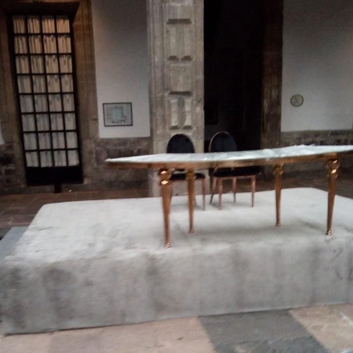 Una mesa y sillas en una habitación con un pilar al fondo.