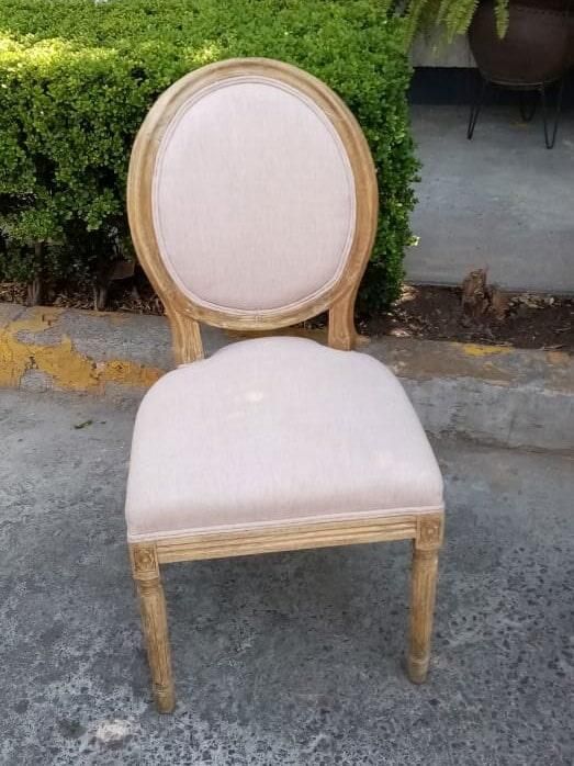 Una silla está sentada en la acera frente a un arbusto.