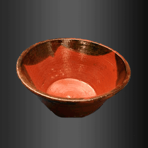 Un cuenco rojo con borde negro reposa sobre una superficie negra.