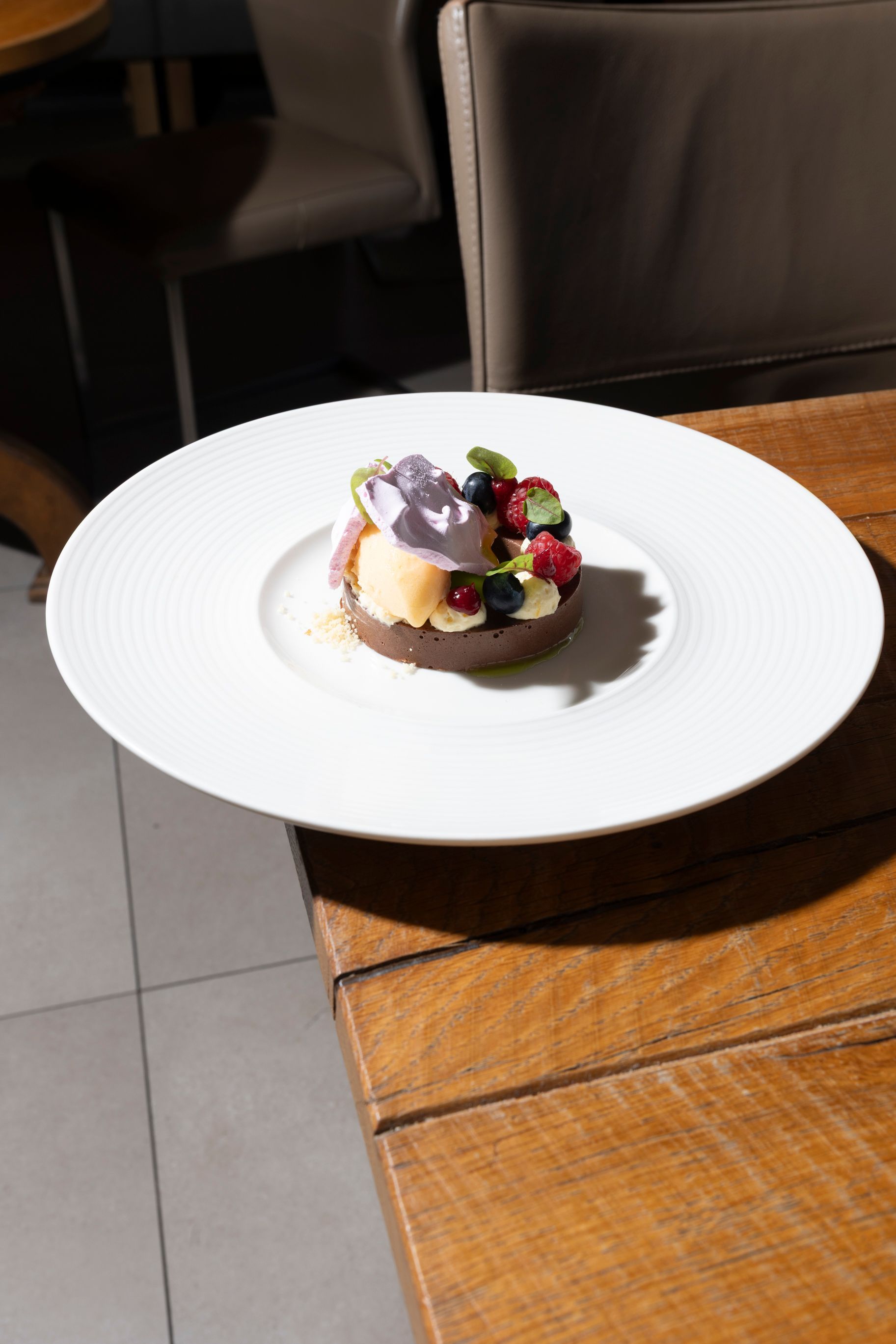 Desserttorte auf einem weißen Teller auf einem Holztisch. Beeren und Schlagsahne garnieren das Gericht.