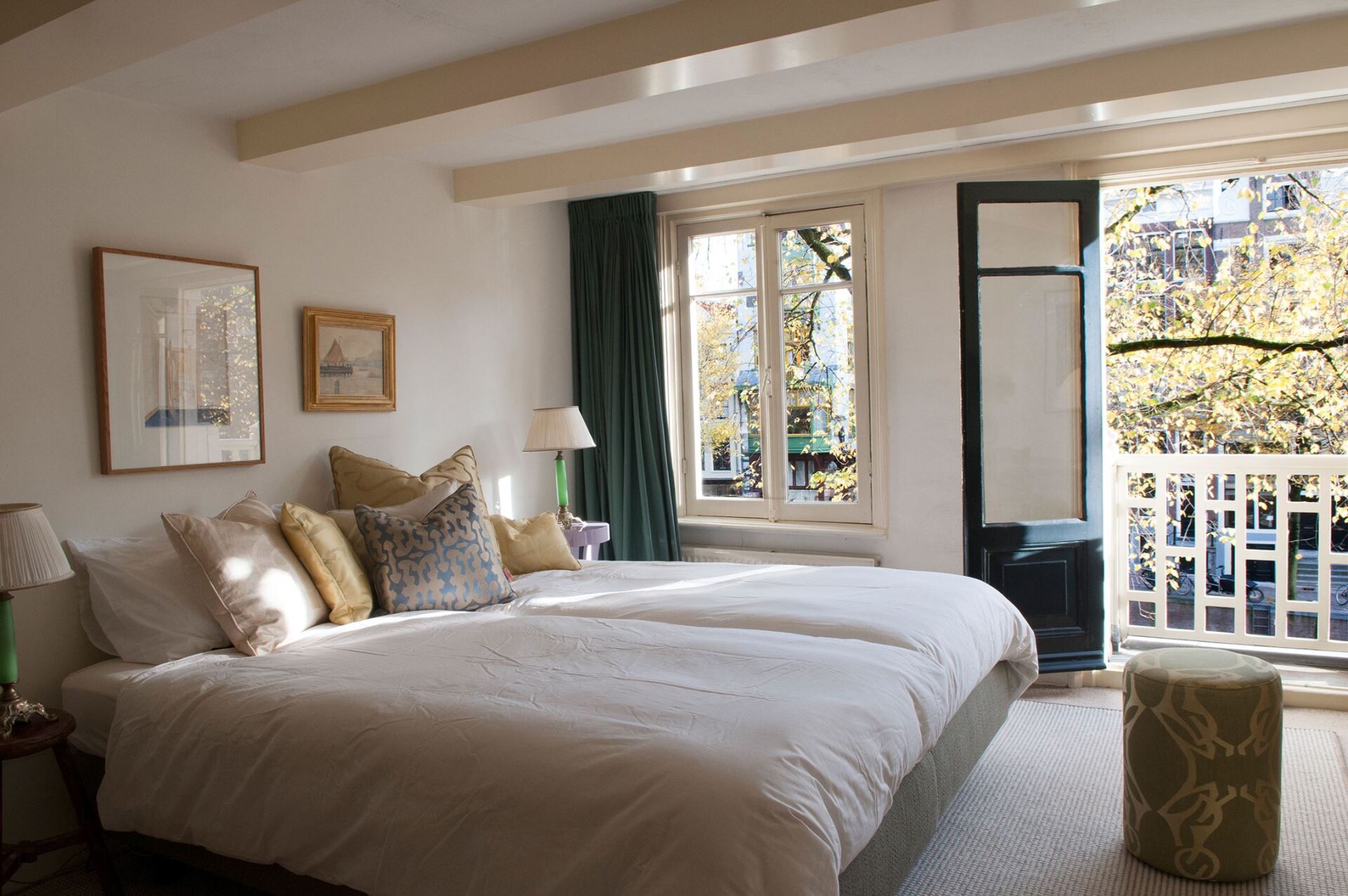 Ein Schlafzimmer mit zwei Betten und einem Balkon mit Bäumen im Hintergrund