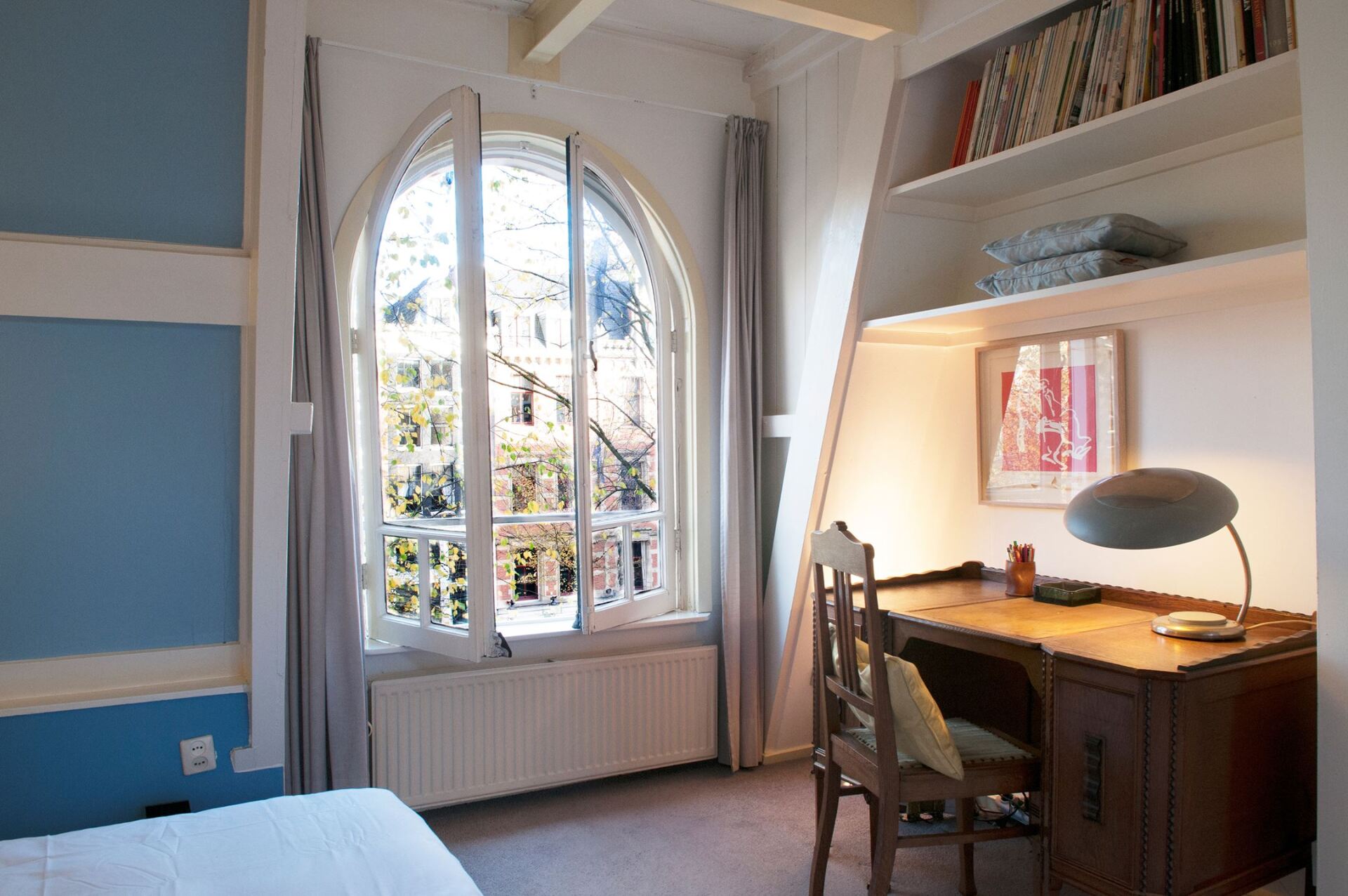 Ein Schlafzimmer mit Schreibtisch und Stuhl vor einem großen Fenster.