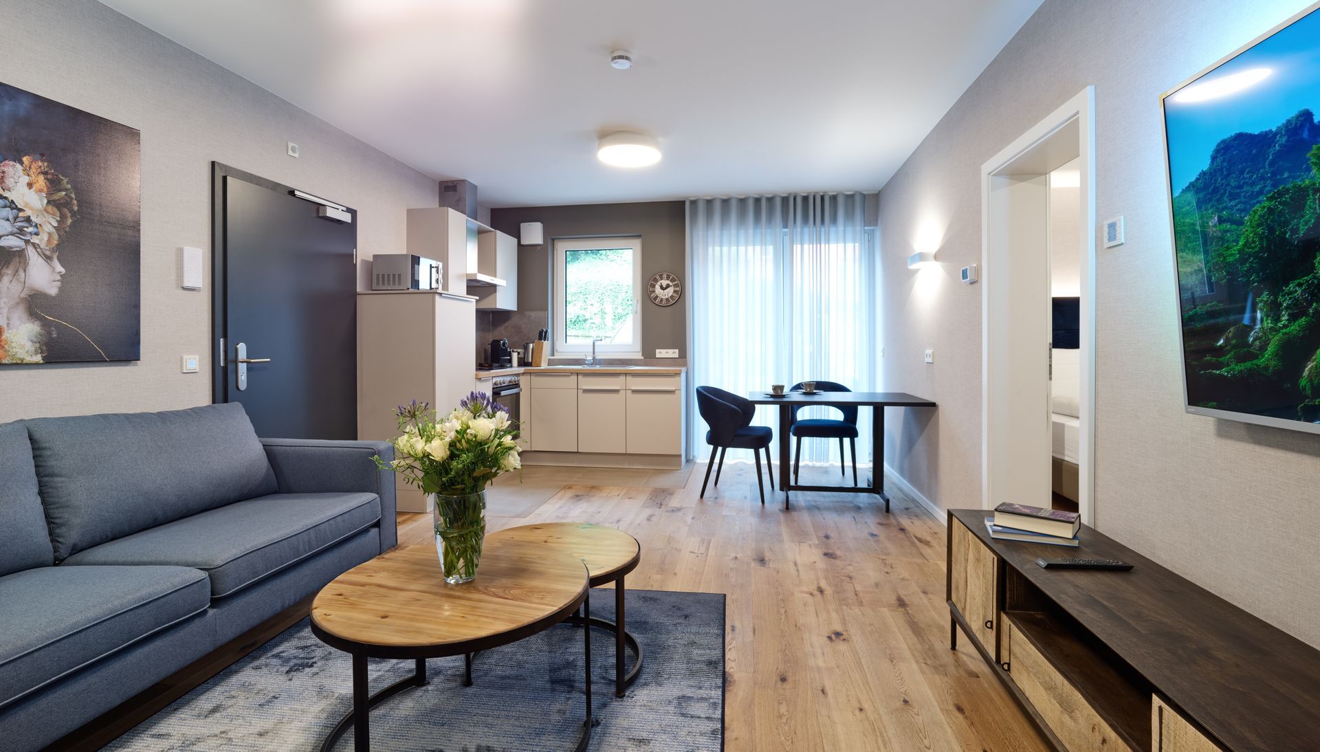 Moderne Wohnungseinrichtung: Wohnzimmer mit Sofa, Küche, Essbereich, Holzböden und Fernseher.