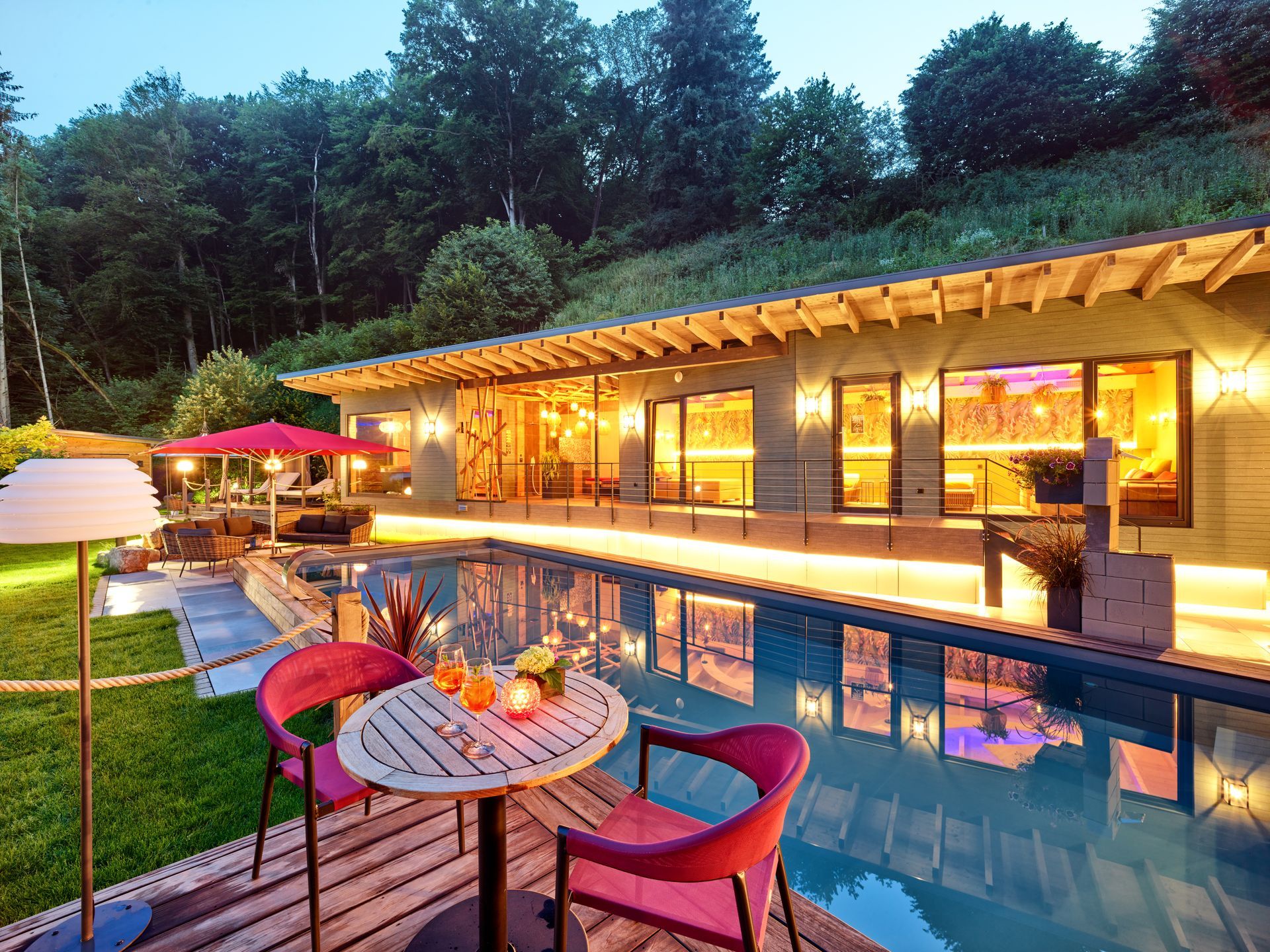 Spa-Bereich im Freien mit Pool, einem Gebäude mit großen Fenstern und einem Tisch mit Stühlen.