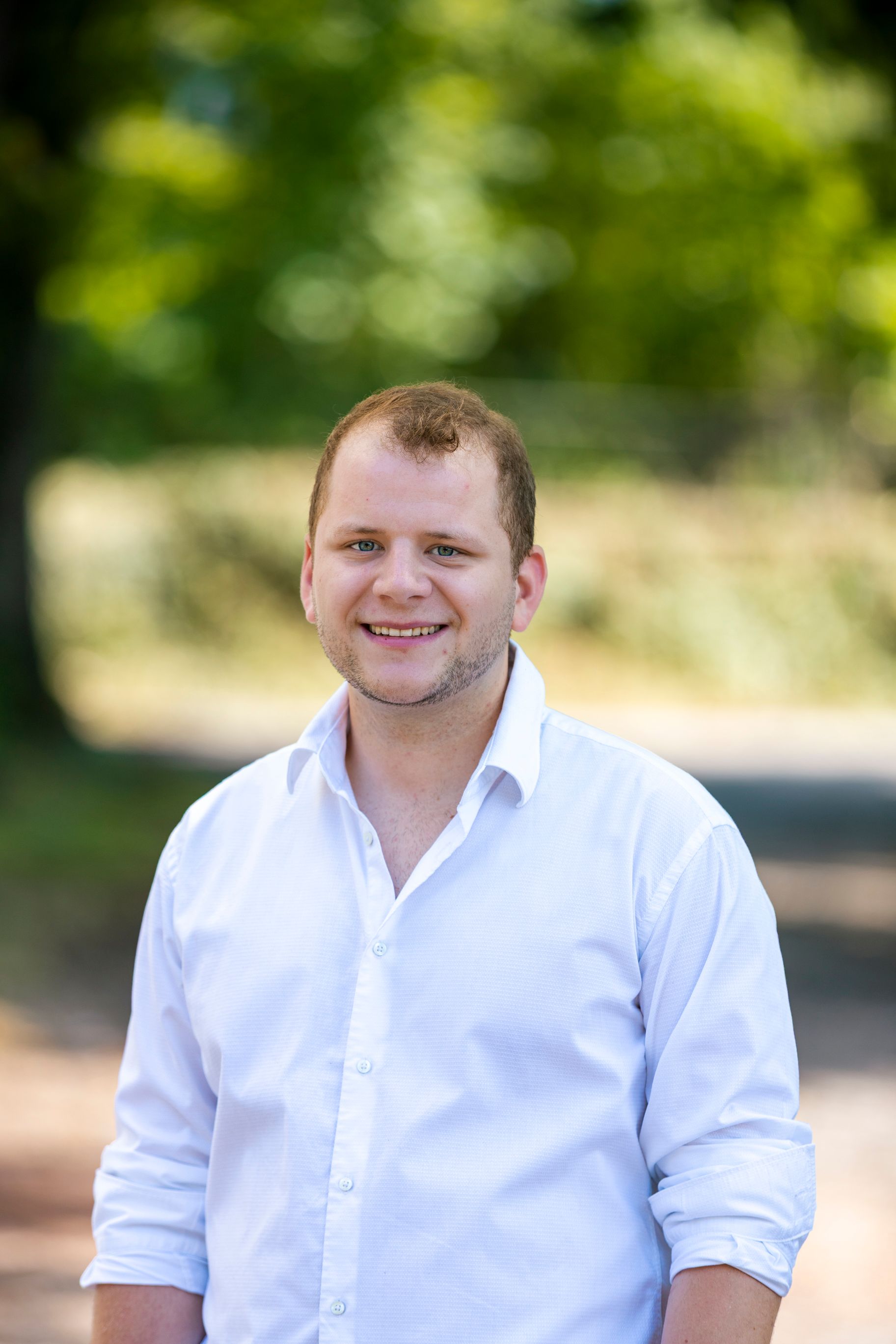 Ein Mann in einem weißen Hemd lächelt in die Kamera.