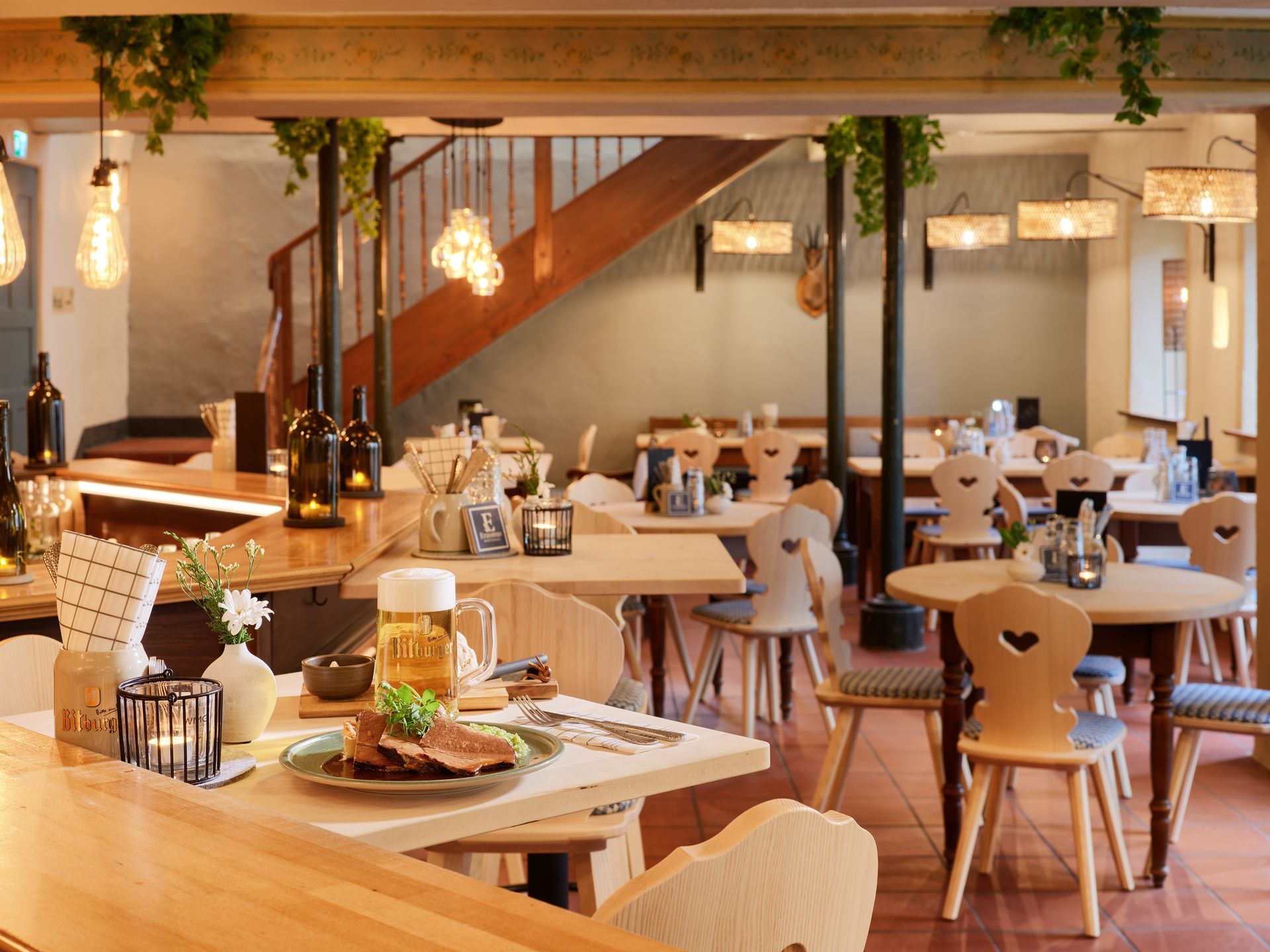 Ein Restaurant mit Tischen und Stühlen und einer Treppe im Hintergrund