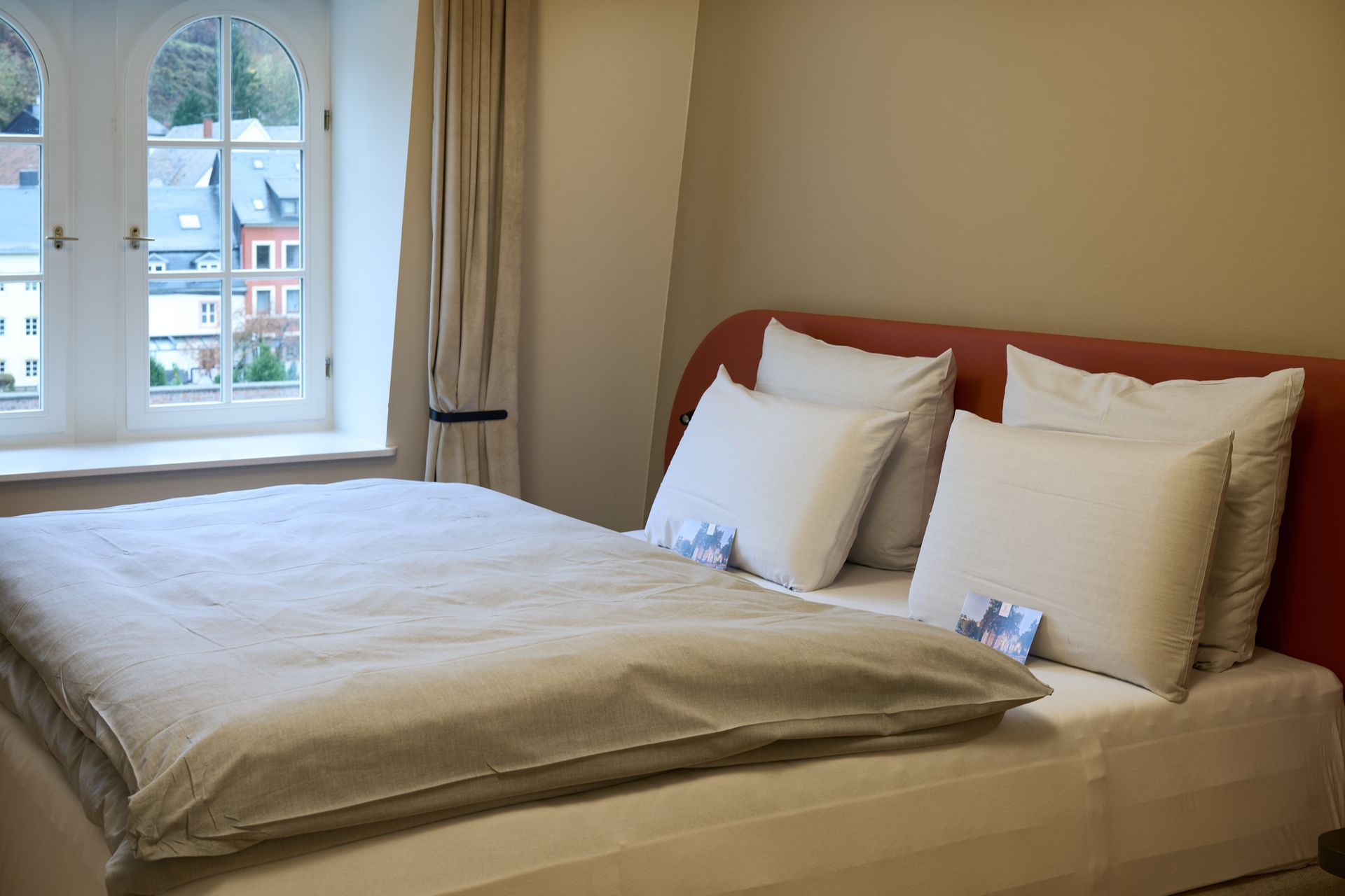 Schlafzimmer mit Bett, Kissen, Fenster und neutralen Wänden.